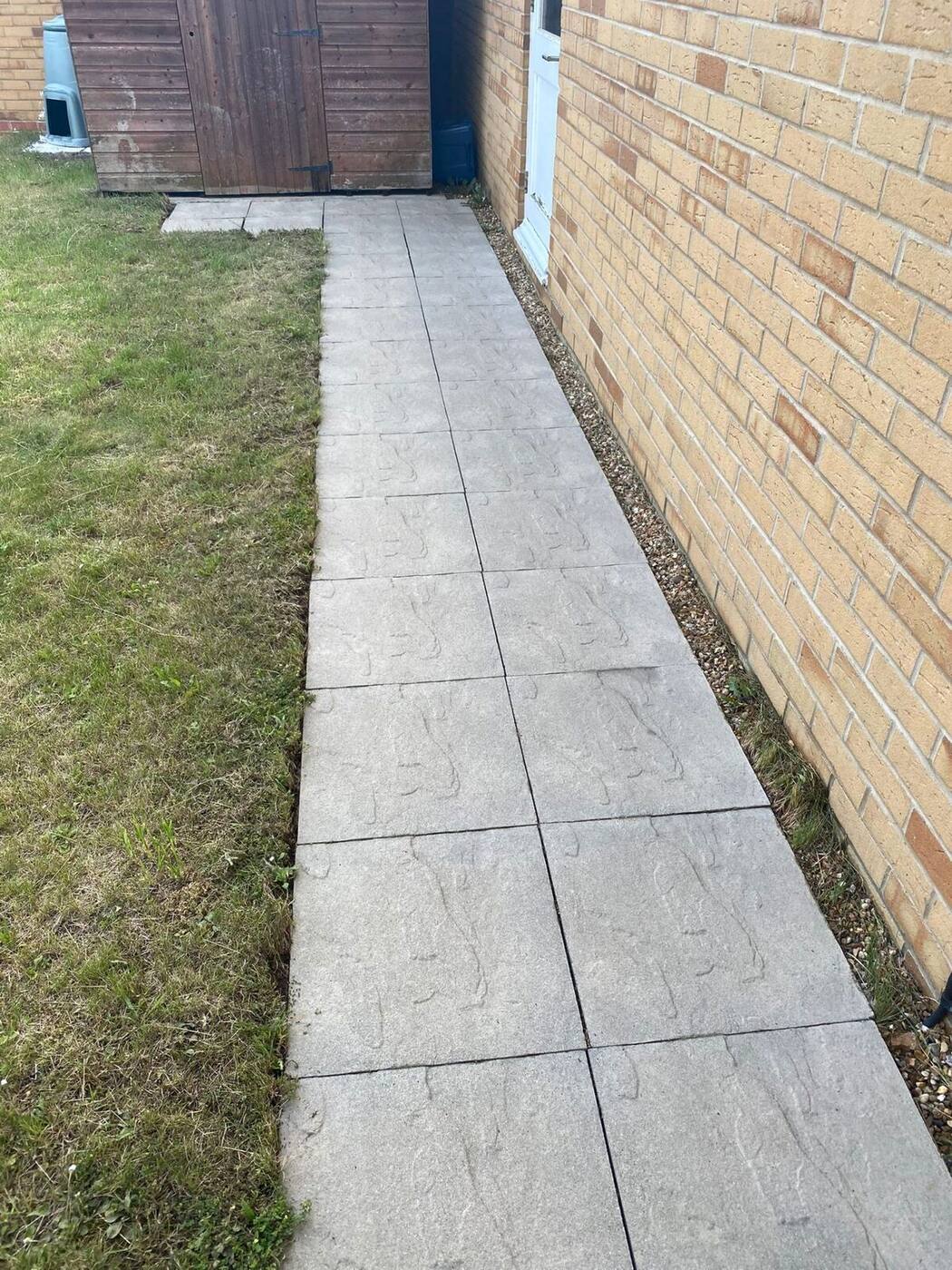 Clean bright path slabs alongside house after professional pressure washing