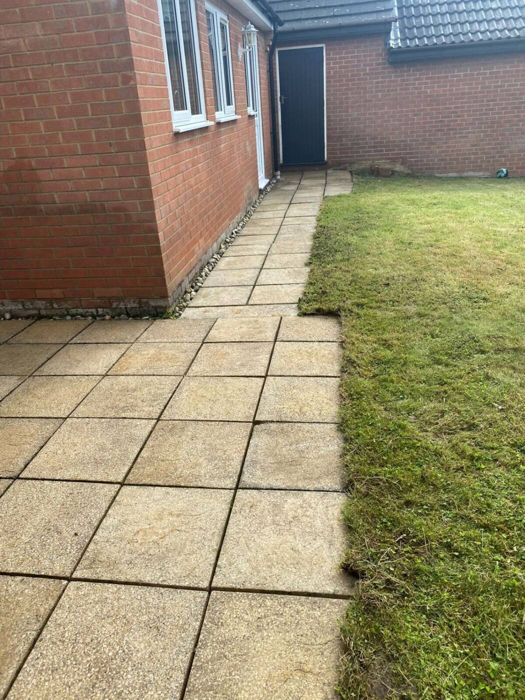 Clean bright paving slabs along house side path after pressure washing